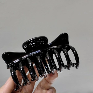 Detailed view of large glossy black hair claw clip with multi-tooth design for thick hair