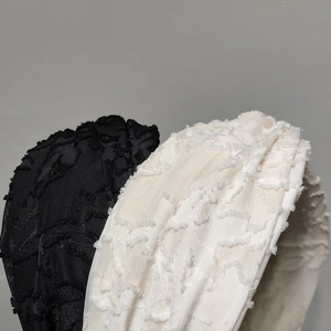 Close-up of black and cream headbands with textured tassel fabric and fringe details