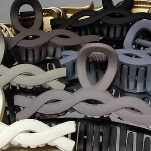 Elegant matte claw clips in assorted neutral colors featuring a woven cross design