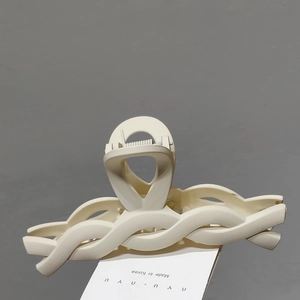 Detail of elegant cream matte hair claw clip with twisted woven design and smooth finish