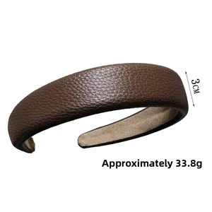 Détail d'un serre-tête en cuir marron foncé de 3 cm de large avec texture litchi
