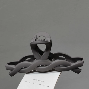 Detail of matte dark grey hair claw clip with intertwined wave design and metal spring