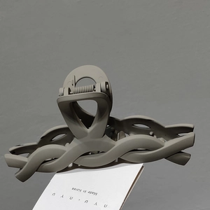 Close-up of matte grey-green claw clip with a refined wave design and metal spring
