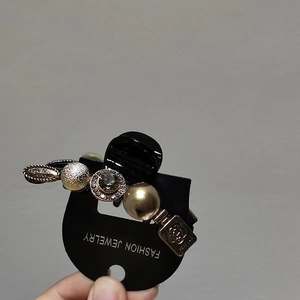 Close-up of elegant black hair claw clip featuring gold camellia and perfume charms