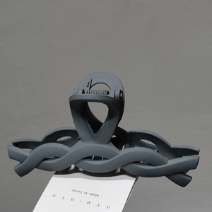 Close-up of a matte dark grey shark hair claw clip with a unique woven wave design texture