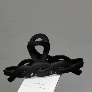 Detail shot of a matte black hair claw clip with a wave-shaped woven hollow design