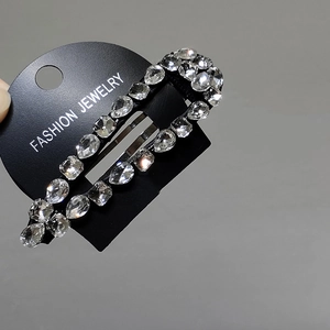 Close-up of sparkling white crystal BB hair clip on a black display card