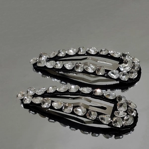 Detailed view of two vintage crystal snap clips with sparkling teardrop and oval stones
