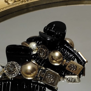 Detail view of black claw clip with champagne pearls, rhinestones and camellia charm