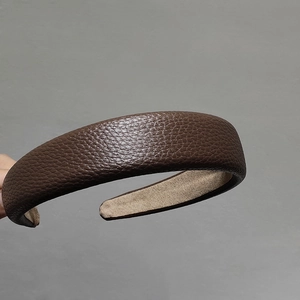 Détail du cuir grainé marron foncé sur un serre-tête large et rembourré élégant