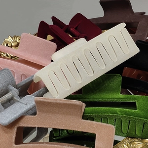 Close-up of large matte velvet hair claw clips in various colors on a gold tray