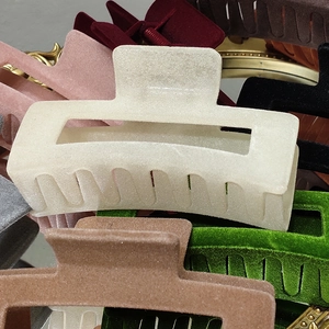 Macro shot of large flocked hair claws in various colors on a vintage gold mirror surface