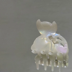 Dettaglio di un piccolo fermaglio per capelli perlato con orecchie di gatto e riflessi viola