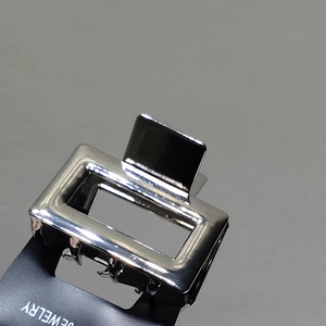 Close-up of silver metal hair claw with rectangular hollow frame and jagged teeth