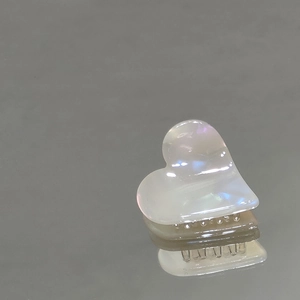 Dettaglio di un fermaglio per capelli a cuore con finitura perlata e iridescente