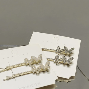 Elegantes Set aus goldenen Schmetterlings-Haarspangen mit Perlen und Strass auf weißer Karte