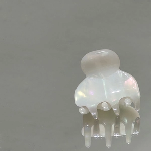 Vista macro di una piccola molletta per capelli perlata con finitura olografica e design