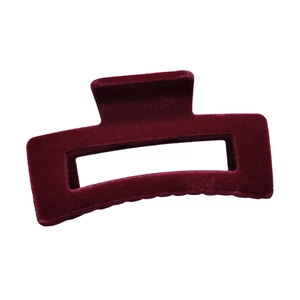 Macro detail of a large burgundy velvet hair claw clip with geometric hollow design