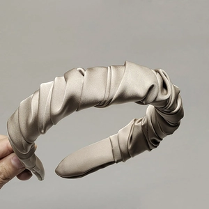 Detail of champagne gold satin headband with elegant pleated texture and wide padded design