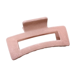 Close-up of a large pink flocked hair claw clip featuring a soft velvety matte texture