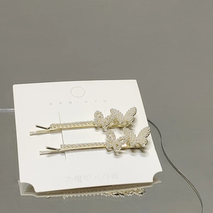 Detailansicht von zwei goldenen Perlen-Schmetterlings-Haarspangen auf Markenkarte
