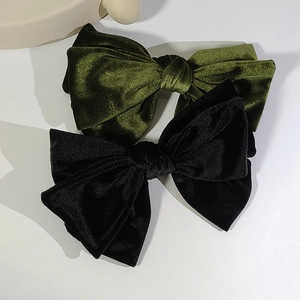 Macro shot of large velvet bow hair clips in olive green and black soft fabric