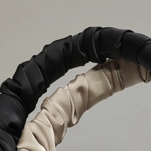 Detailed view of champagne and black pleated satin headbands with rich fabric texture