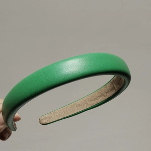 Detail shot of green leather headband featuring litchi texture and beige suede lining