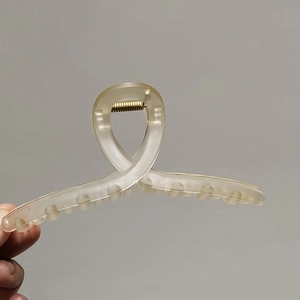 Gros plan sur une grande pince à cheveux mate beige avec un ressort en métal doré durable