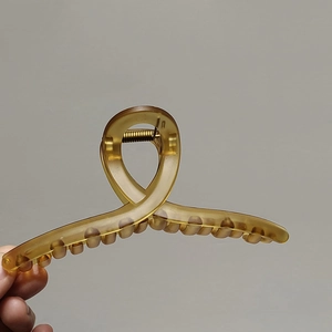 Détail d'une grande pince à cheveux en résine ambrée avec ressort en métal doré brillant