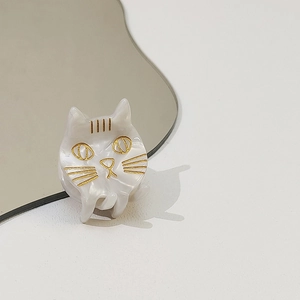 Détail d'une pince à cheveux chat blanc nacré avec des finitions dorées élégantes