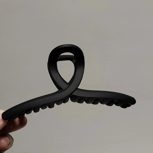 Vue détaillée d'une grande pince à cheveux noir mat avec un design croisé moderne pour femme