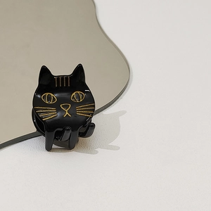 Détail de la pince à cheveux chat noir en acétate avec dorures et reflet sur miroir