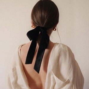 Elegant French style black velvet hair scrunchie with long ribbons on a model's ponytail