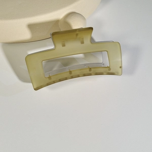 Detail of matte light green square hair claw clip on a textured beige surface