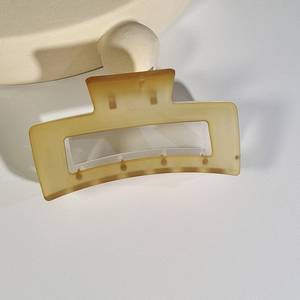 Close-up of a matte amber rectangular hair claw clip on a textured surface