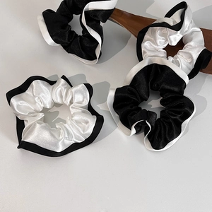 Détails de chouchous en satin contrastés noir et blanc avec des bords ondulés