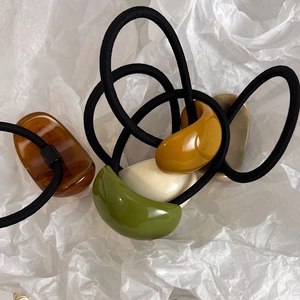 French minimalist oval geometric hair ties in earthy tones on a white textured background