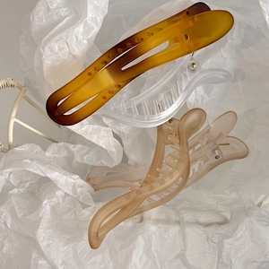 Three elegant matte and glossy large hair claw clips in amber, white, and milk tea colors