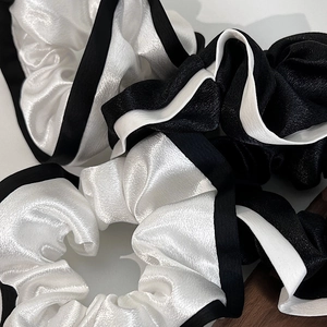 Gros plan de chouchous en satin premium avec passepoil contrasté noir et blanc chic