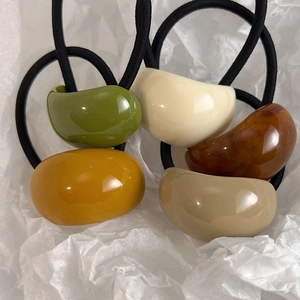 Set of five elegant resin hair ties in olive green, cream, and amber tones on white paper