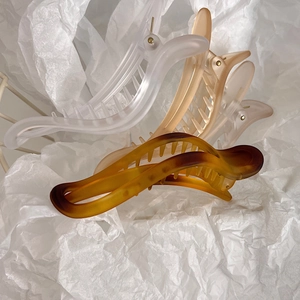 Detail of four matte gradient claw clips in resin on white decorative paper