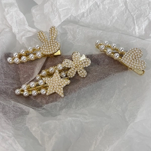 Détail de barrettes dorées avec perles en forme de lapin d'étoile et de coeur