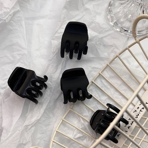 Set of four small black hair claws with matte and glossy finishes on a white background