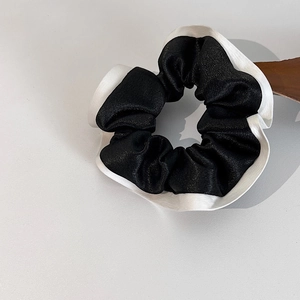 Détail d'un chouchou en satin de soie avec volants contrastés noir et blanc élégants