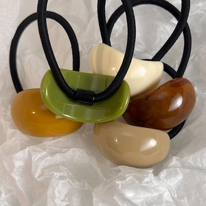 Close-up of elegant oval acrylic hair ties in vintage green, amber, and cream colors