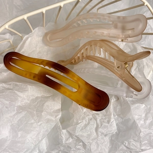 Close-up of matte hair claw clips set in amber and blush pink on a white background