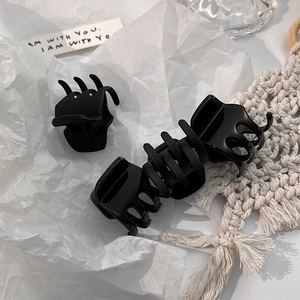 Detail showing matte and glossy black hair claws on a stylish aesthetic background