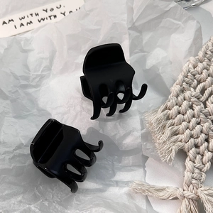 Matte and glossy black mini hair claw clips for high ponytail styling on textured background