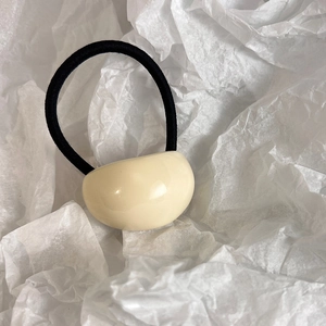 Detail of minimalist cream acrylic pebble ornament on elastic black hair tie for women
